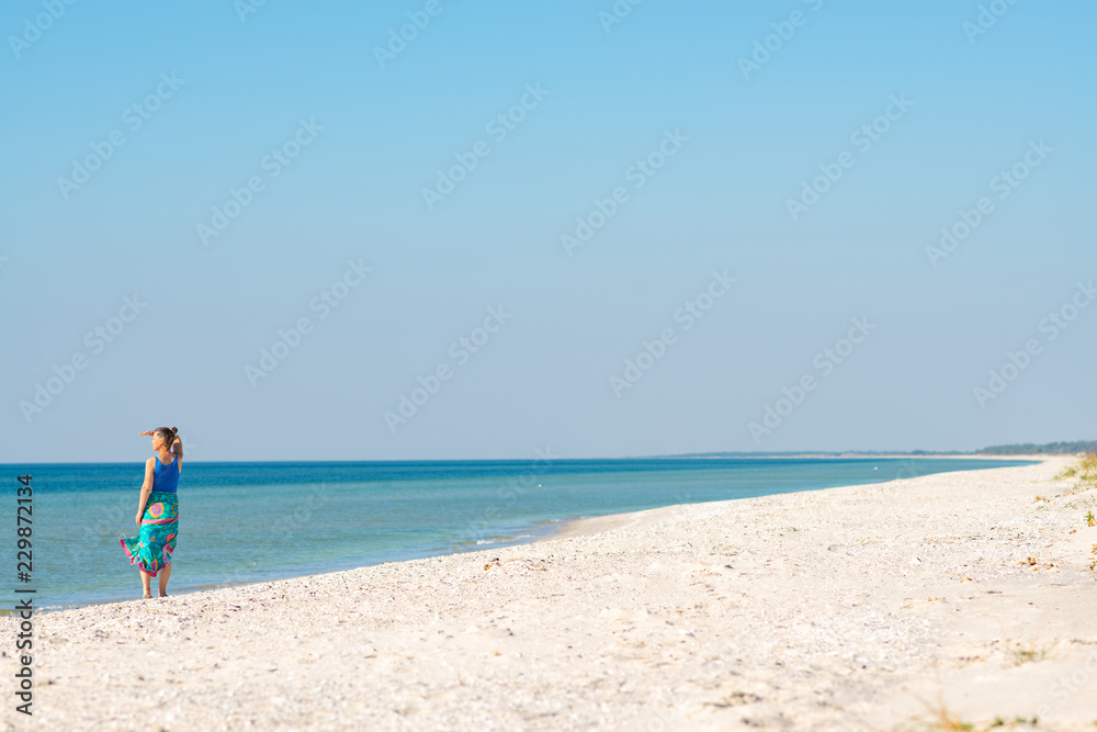 Woman in a pareo walks along the sandy deserted beach Woman in a pareo walks along the sandy deserted beach