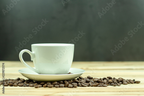 Cup of coffee with coffee beans on wood background.
