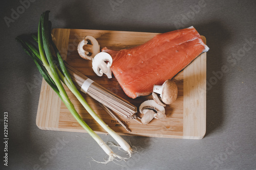 udon noodles, spring onion, mushrooms and salmon on a wooden board in the kitchen photo