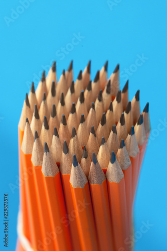 Bunch of orange pencils on blue background close up