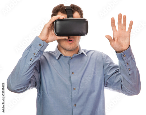 Man in Viara wearing glasses in shirt on white isolated background. Helmet virtual reality gadget concept. Man surprised gestures with his hands
