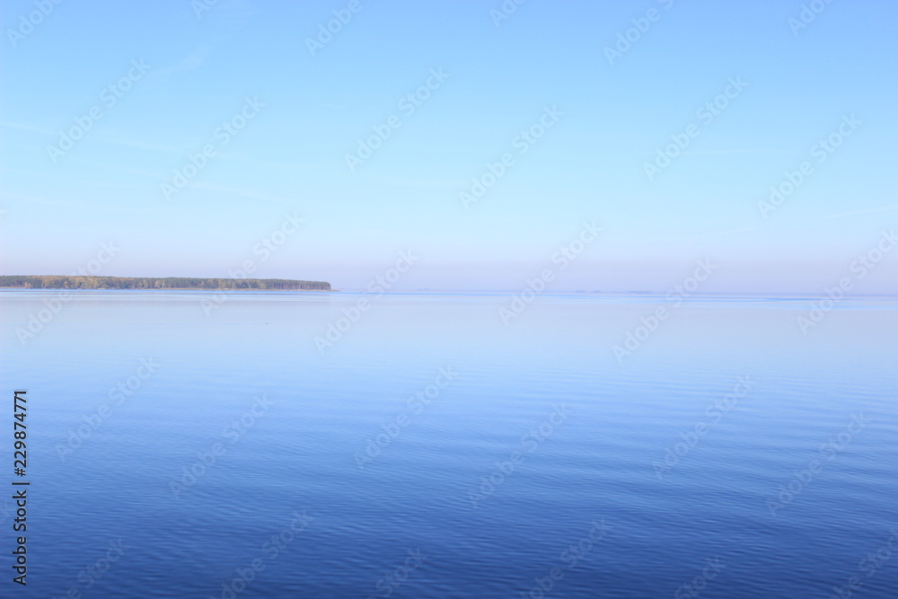 Wide bay of the sea, with the horizon. Blue clear sky on a warm day.