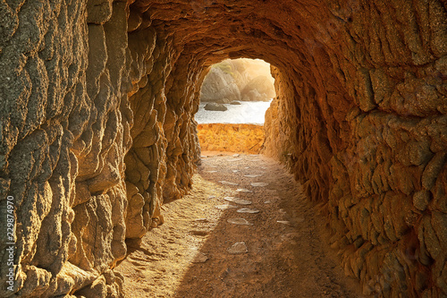 Path through a cave to sunrise over the sea