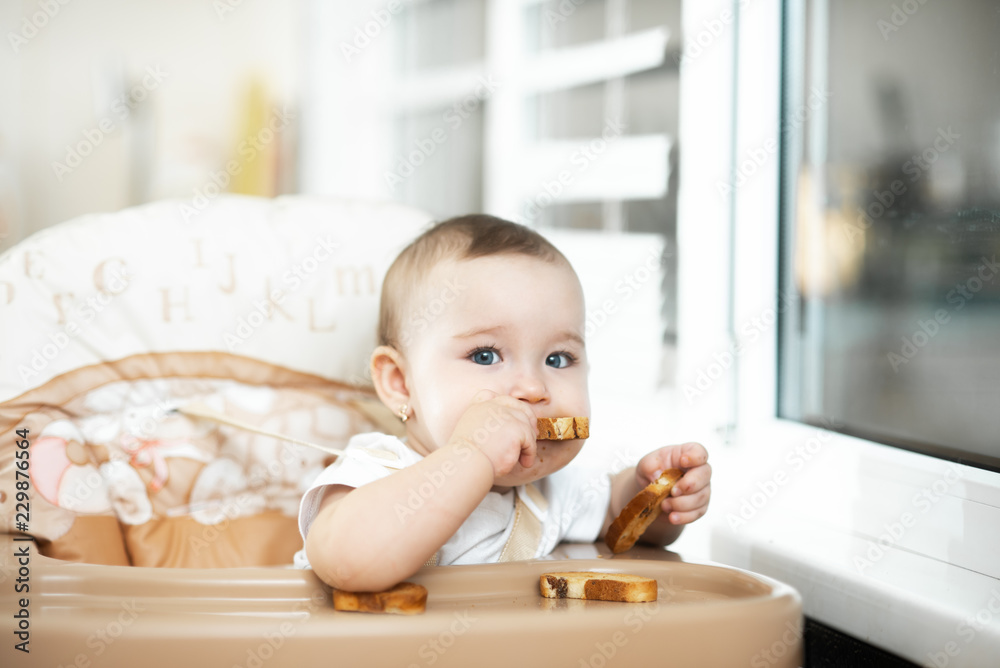 Baby girl eating cracker with raisins in a chair Baby girl eating cracker with raisins in a chair