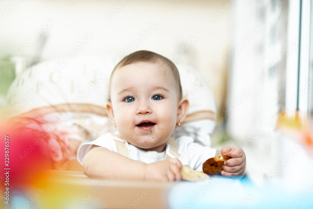 Baby girl eating cracker with raisins in a chair Baby girl eating cracker with raisins in a chair