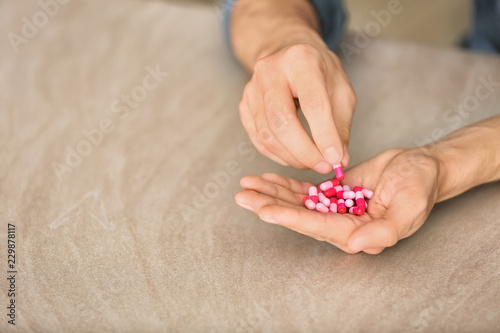 Man holding capsules on table, closeup