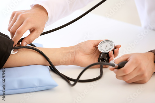 Photos Male doctor measuring blood pressure of female patient in hospital