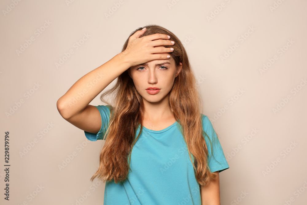 Portrait of beautiful young woman suffering from headache on light background