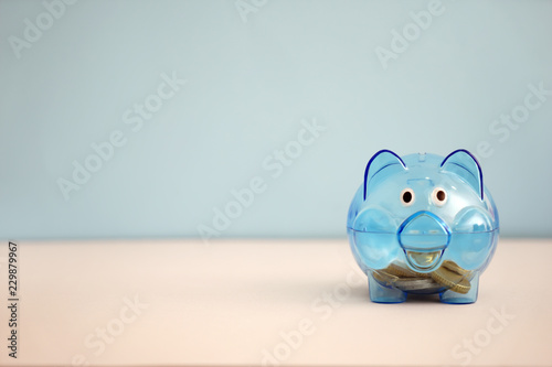 Cute piggy bank with coins on color table