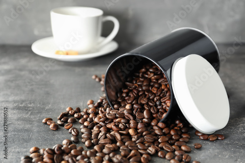 Overturned container with roasted coffee beans on table