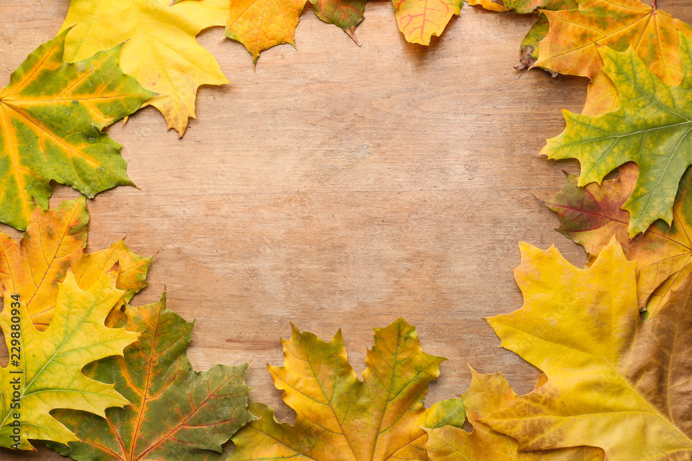 Frame made of autumn leaves on wooden background