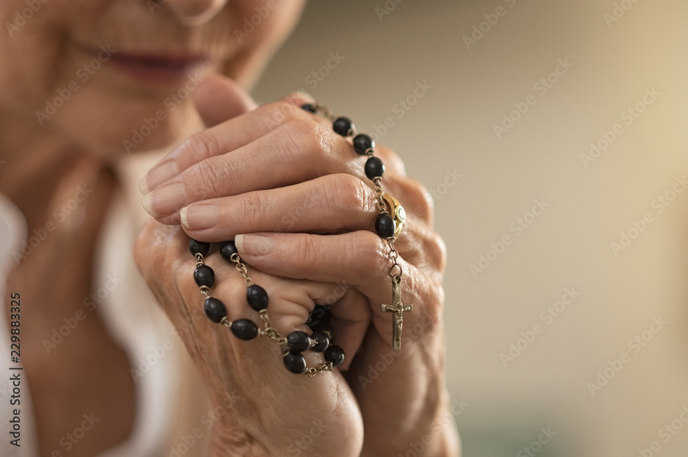 Naklejka premium Hands holding rosary and praying