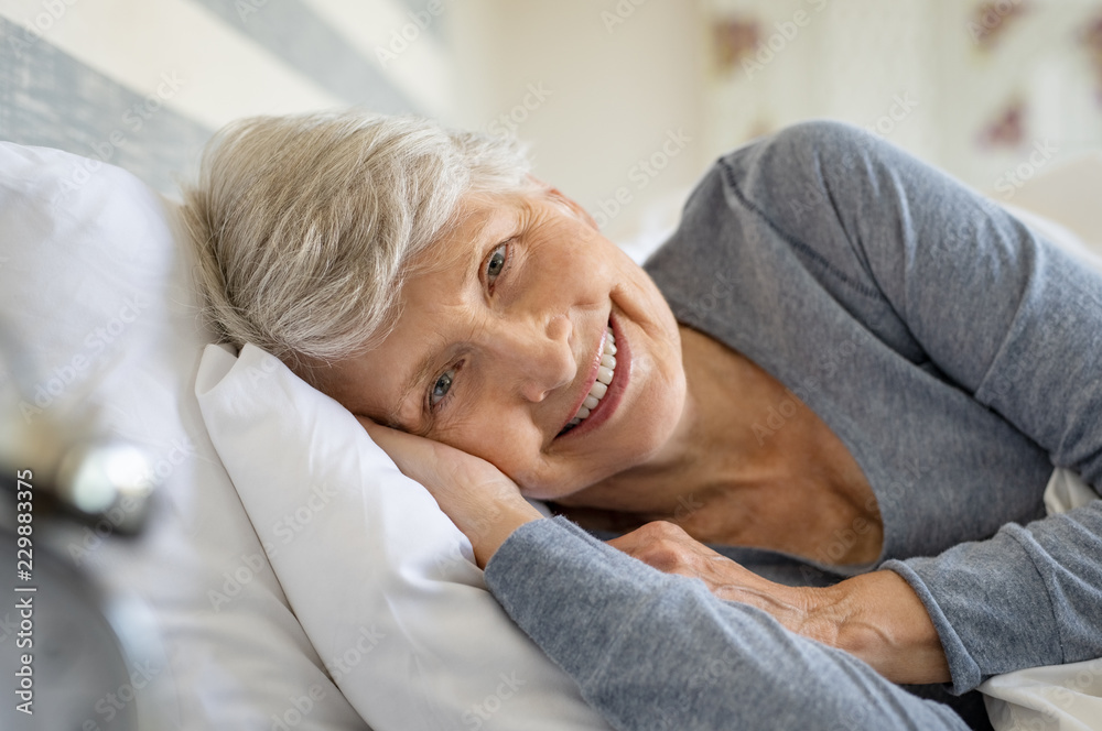 Senior woman resting on bed - obrazy, fototapety, plakaty 