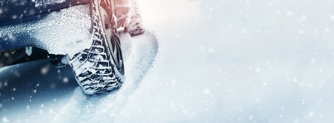 Car tires on winter road covered with snow. Vehicle on snowy way in the morning at snowfall