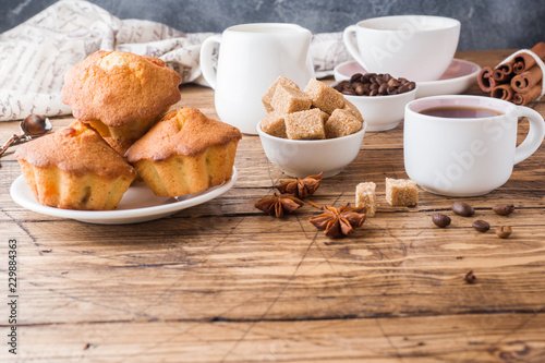 Breakfast coffee with milk, pastries, brown sugar and cinnamon with anise on wooden background. Copy space