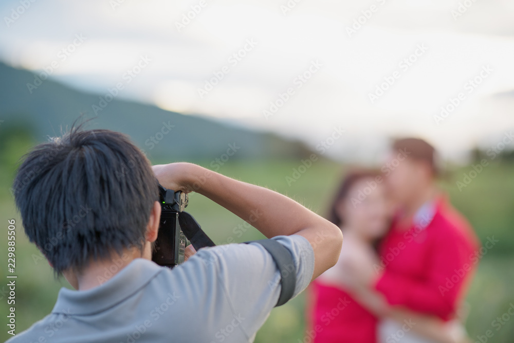 Naklejka premium wedding photographer in action, wedding photographer takes pictures of the bride and groom in nature. Behind the scene of photogrphy working concept.