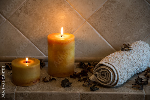 relaxing spa background with candles, some wooden petals and a towel