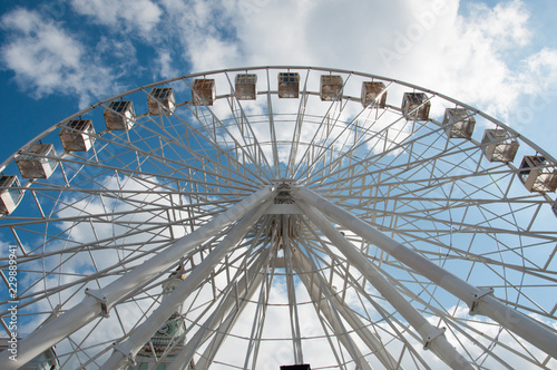 Ferris wheel in an amusement park, view from below. Sky background with clouds with place for text.