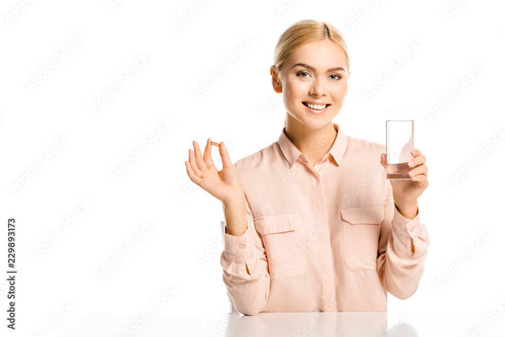 smiling attractive woman holding glass of water and pill isolated on white, looking at camera smiling attractive woman holding glass of water and pill isolated on white, looking at camera