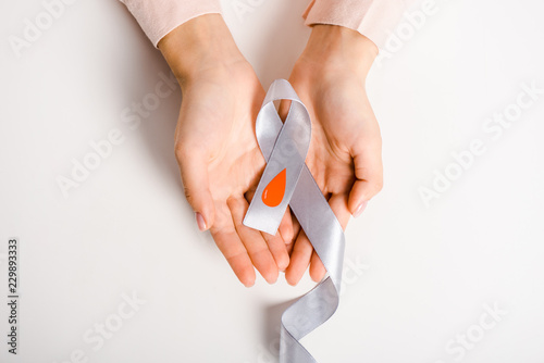 cropped image of woman holding ribbon with blood drop symbol isolated on white, diabetes concept