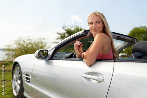 travel, road trip and people concept - happy young woman in convertible car