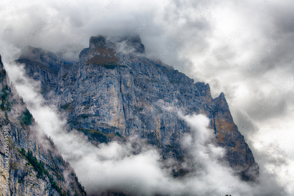 Wengwald cliff Lauterbrunnen Swiss in steel-blue contrast surrounded by mystic clouds