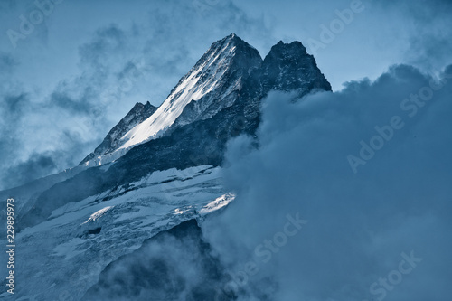 Closeup of summit Nässihorn Grindelwald with glacier and snow during sunrise framed by clouds