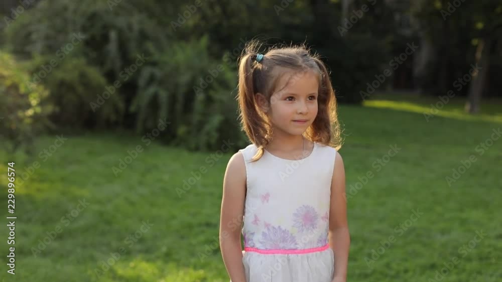 Little pretty Caucasian lady wearing romantic dress looking away. Portrait of wonderful child with brown eyes smiling. Outside. Sunny day. Park. Little pretty Caucasian lady wearing romantic dress looking away. Portrait of wonderful child with brown eyes smiling. Outside. Sunny day. Park.