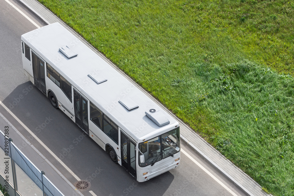 White city bus traveling on the highway, top view.