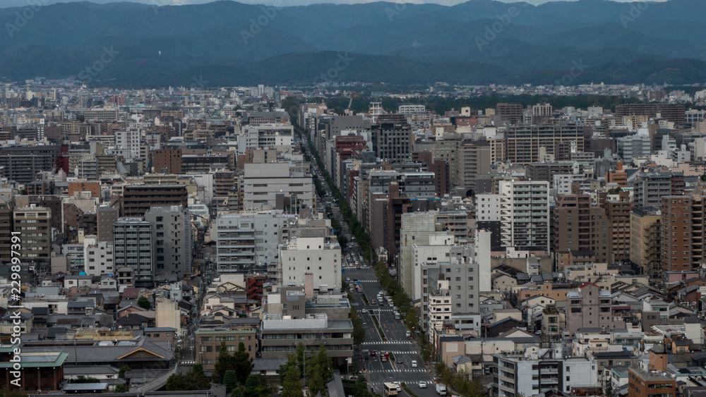 Obraz premium Aerial shots of the city of Kyoto. Skyscrapers and buildings expand out into the distance of the Japanese city as a stormy sky and clouds form over the cityscape.