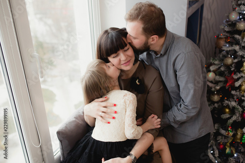 Family with a daughter is sitting at the window and kissing