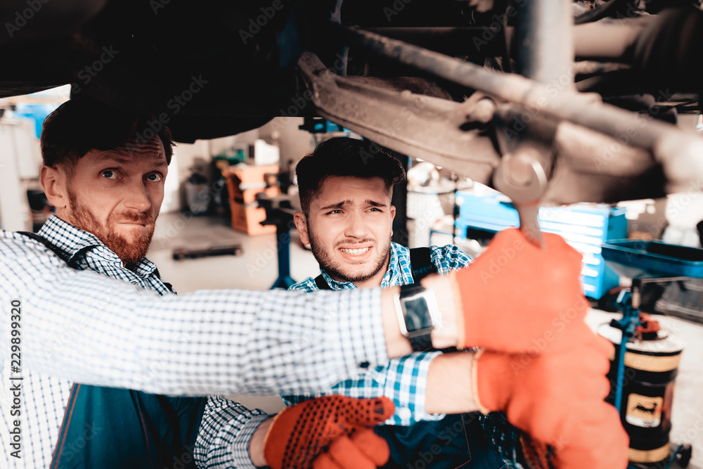 Obraz premium Young Mechanics Repairs Automotive Hub In Garage.