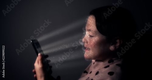 Young child using a smart phone with facial recognition technology with 3D face mapping