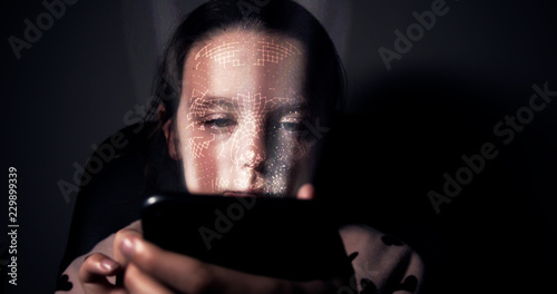 Young girl having her face scanned by her smart phone. Facial recognition concept