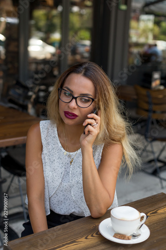 Elegant business female in an outdoor cafe speaking over mobile phone