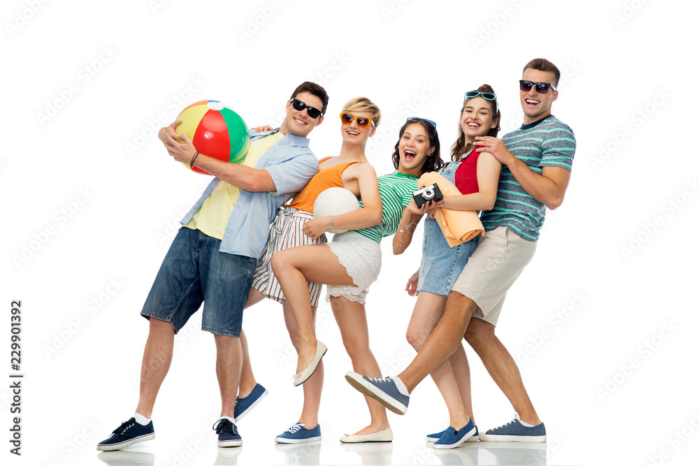 Fototapeta premium summer holidays and people concept - group of happy smiling friends in sunglasses with beach ball, volleyball, towel and camera over white background