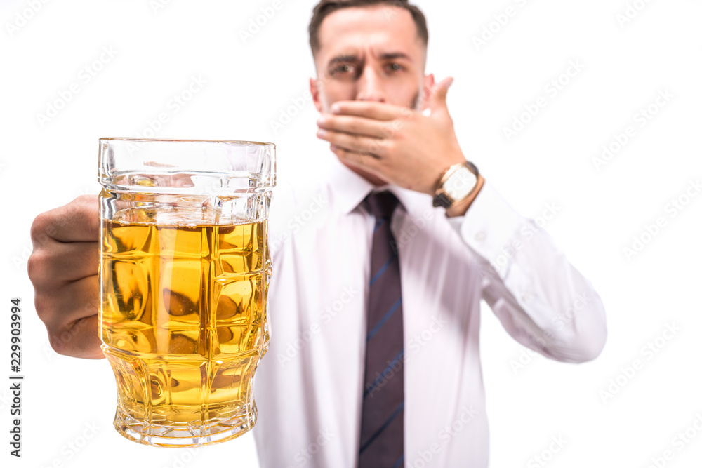 selective focus of businessman covering mouth and holding glass of unhealthy beer isolated on white selective focus of businessman covering mouth and holding glass of unhealthy beer isolated on white
