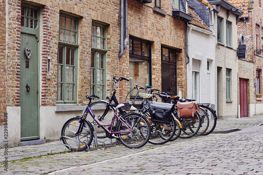 Traditional medieval town. Narrow paved street with old brick houses and bikes near entrance