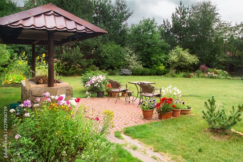 Backyard Patio Area with Fireplace and Furniture. Green Party area. Barbecue Area. Stone.
