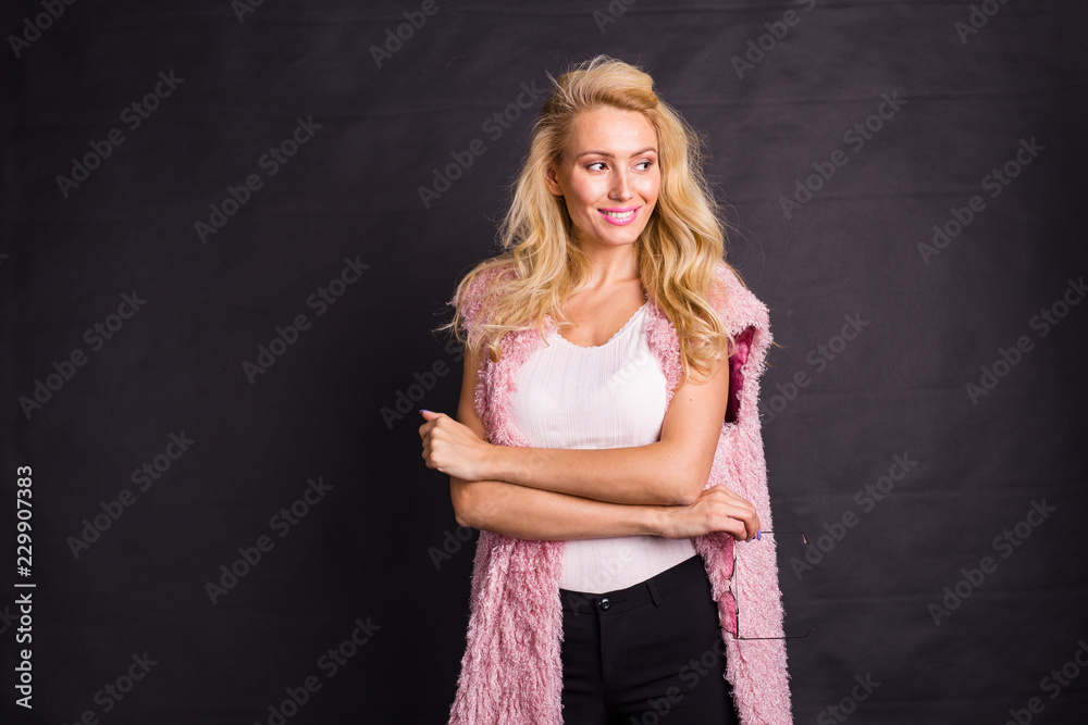 Modeling, fashion, people concept- young serious blonde in pink coat over the black background with copy space Modeling, fashion, people concept- young serious blonde in pink coat over the black background with copy space