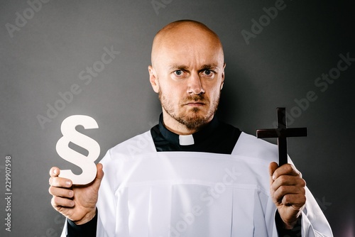 Catholic priest in white surplice holding crucifix and paraphaph. photo