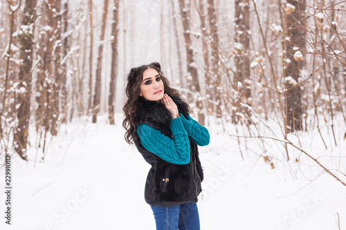 Young pretty woman walking in the winter snowy park at sunny day