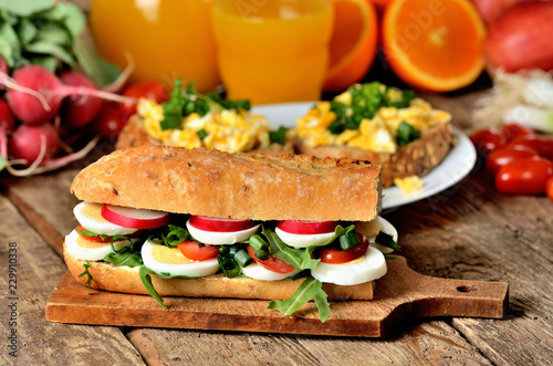 Baguette sandwich with egg, arugula salad, tomatoes and radish