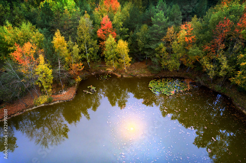 Luftbild von einem kleinen See in dem sich die Herbstsonne spiegelt