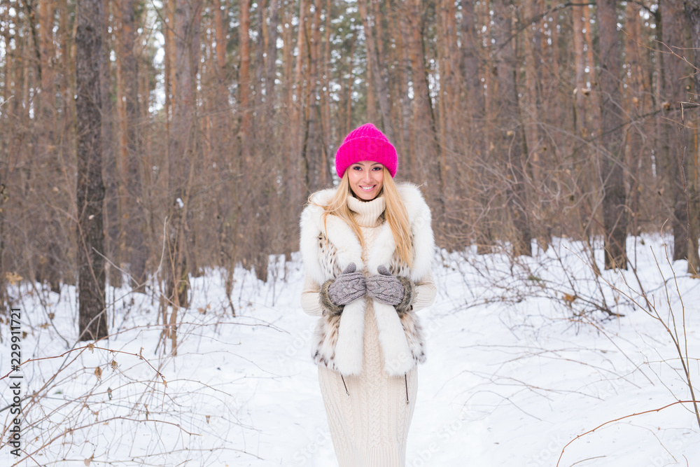 Fototapeta premium Fashion and people concept - Lovely young woman in warm jacket in winter park