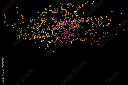 Multicolor gold glitter stars on a dark background. Flat lay. Copy space for text. Night, space or universe concept.