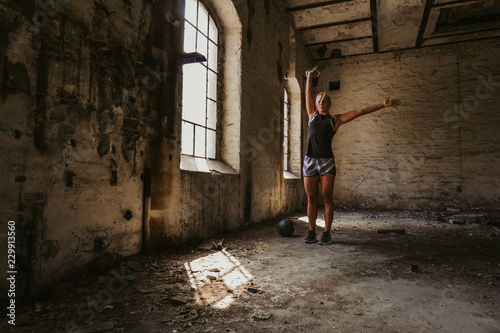 Athletic woman holding kettlebell up in an old building © sasamihajlovic