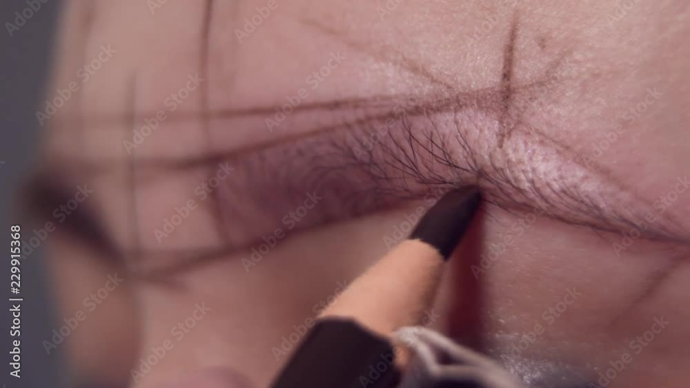 drawing contours on the eyebrows of a woman for applying permanent makeup in a beauty salon