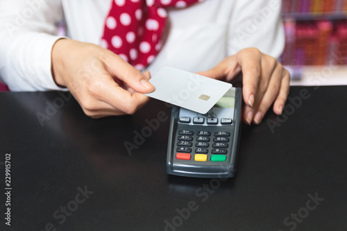 Hands of a female shop assistant holding a credit card and makin