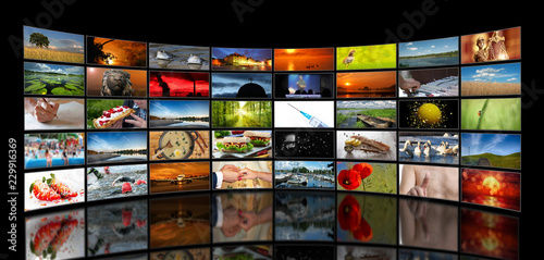 Wall of stacked TV screens with various motifs on a black background photo